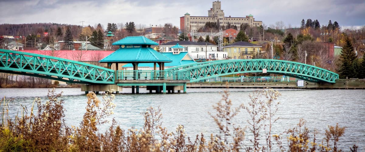 A turquoise bridge over a river with a building in the background.
