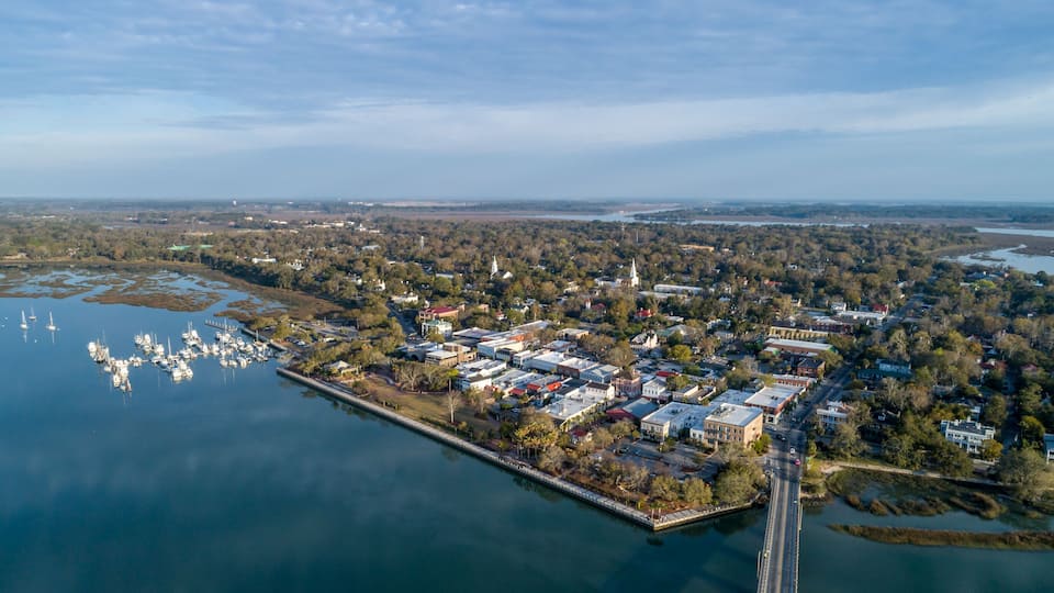 An aerial view of a town with a marina, a bridge, and a river.