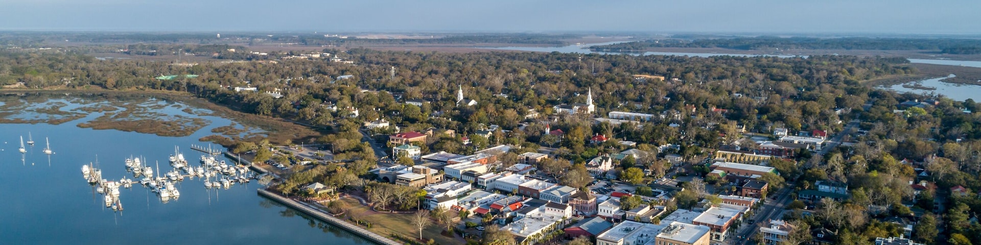 An aerial view of a town with a marina, a bridge, and a river.