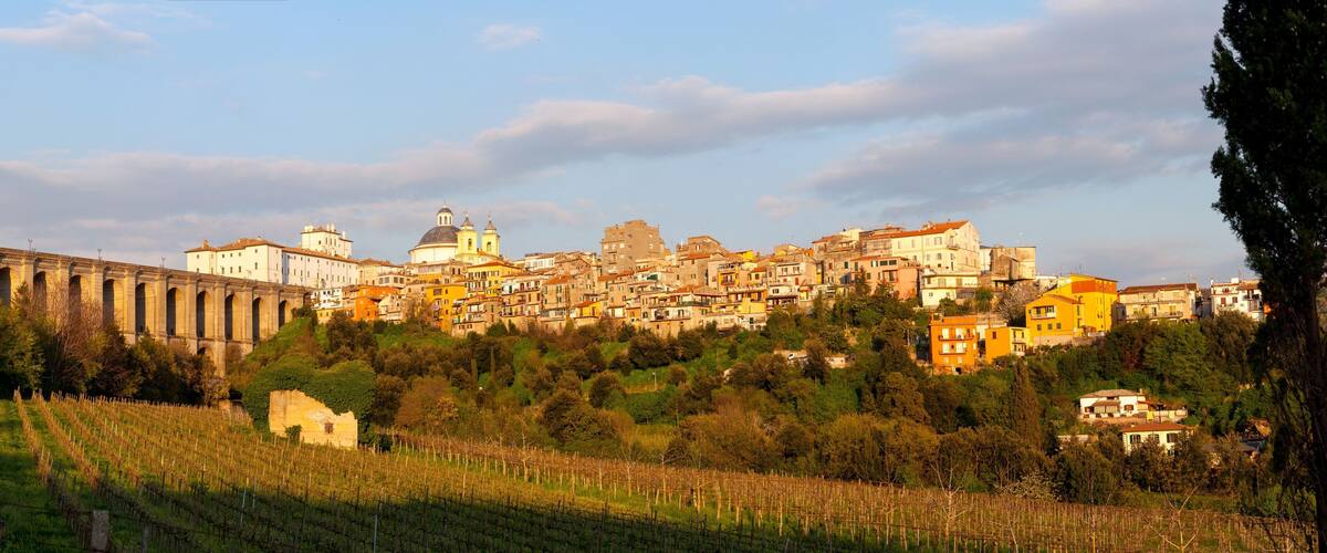 A hillside town with historic architecture, vineyards, and a prominent aqueduct.
