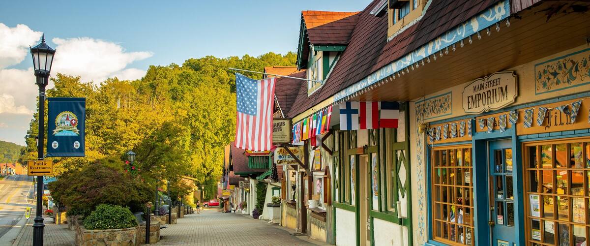 A historic Main Street with traditional architecture, American flags, and a sign for the Emporium.