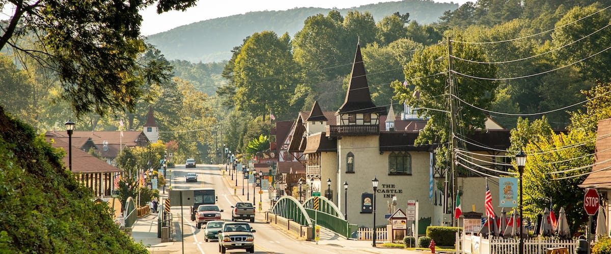 A town street with historic buildings, a bridge, and a hill in the background.