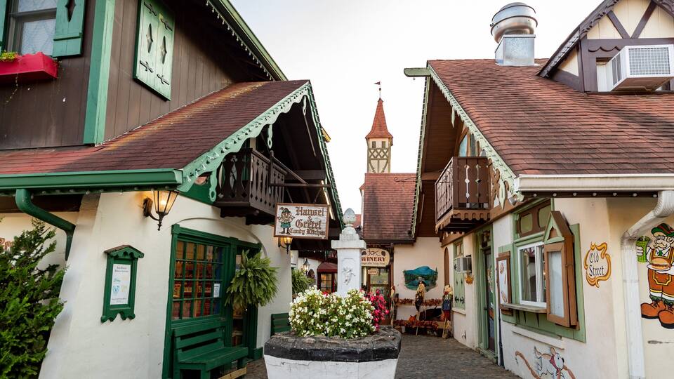 A narrow street with traditional European architecture, including half-timbered houses and a church steeple.