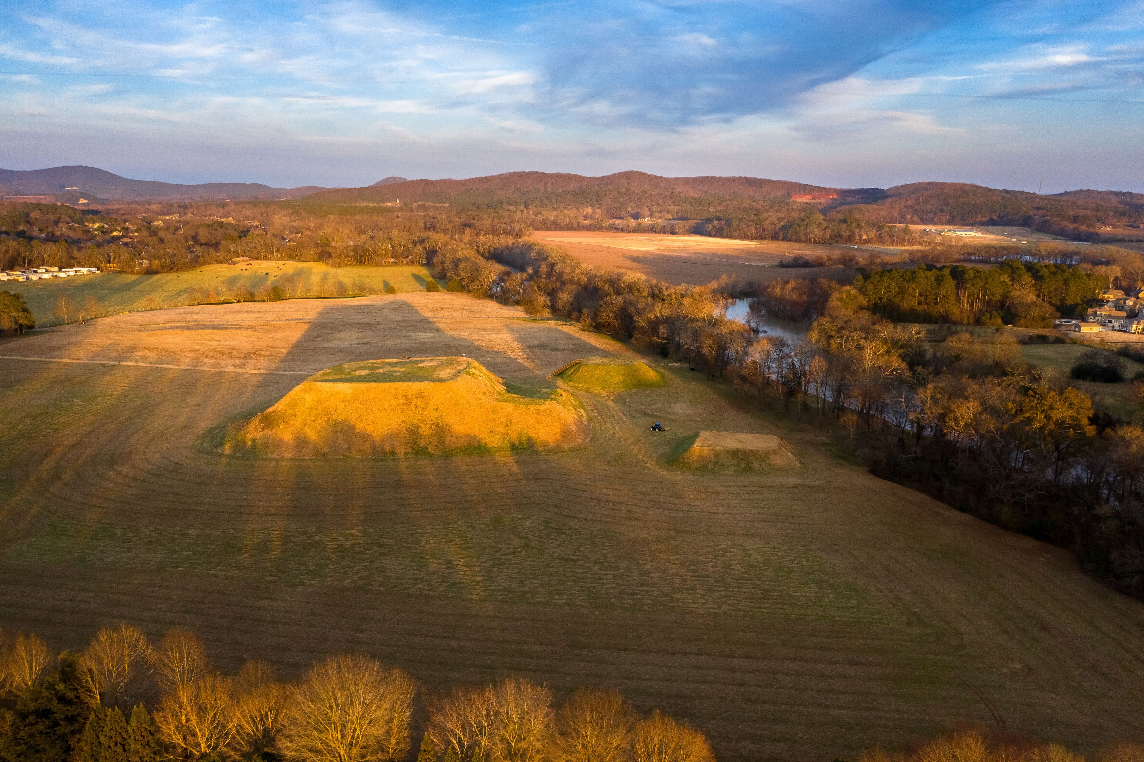 A vast landscape with rolling hills, a river, and scattered trees.