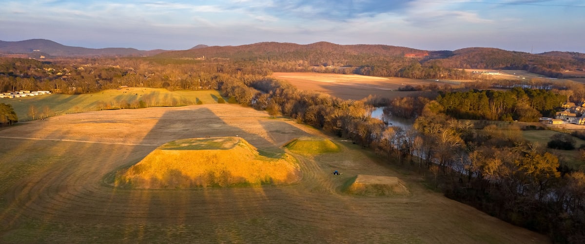 A vast landscape with rolling hills, a river, and scattered trees.