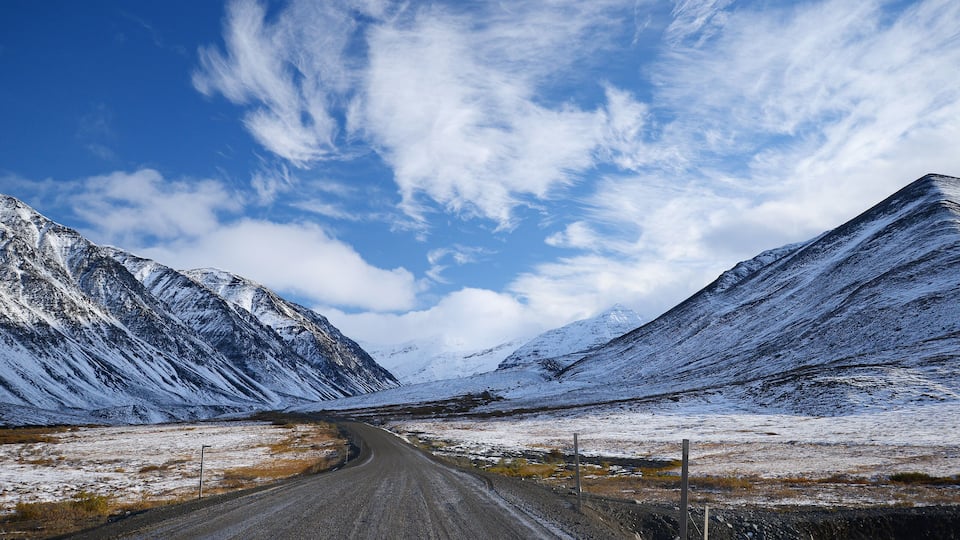 A snow-covered mountain road with a clear blue sky.