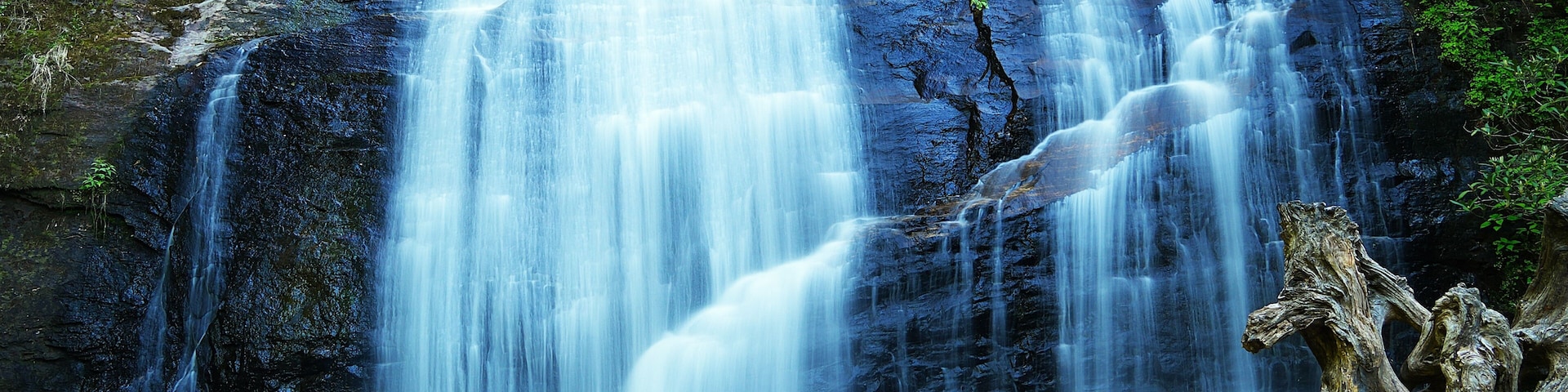 Una cascada se precipita sobre un risco rocoso hacia un estanque en la base.