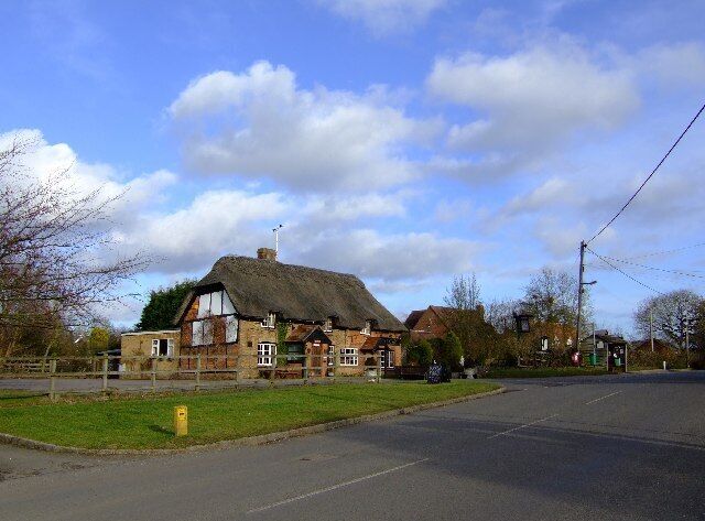 A thatched-roof building with a grassy area in front.