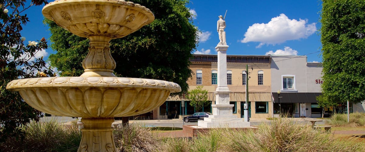A fountain with a statue in the background.
