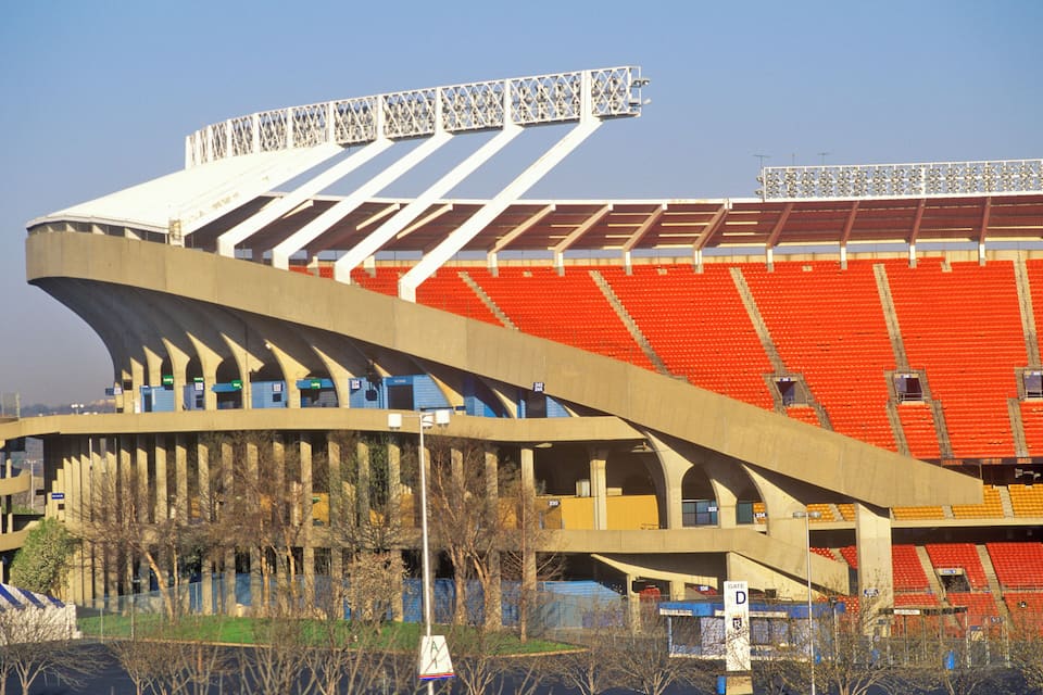 A stadium with red seats and a curved roof structure.
