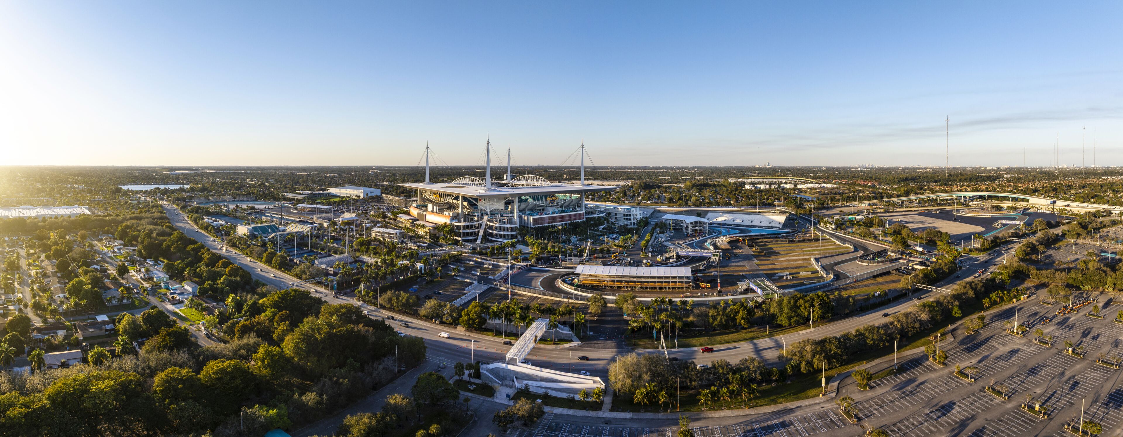 Miami Gardens, USA - 23 February 2026: Aerial view of Hard Rock Stadium bathed in the warm glow of a setting sun, its sleek architecture contrasting with the surrounding lush greenery.