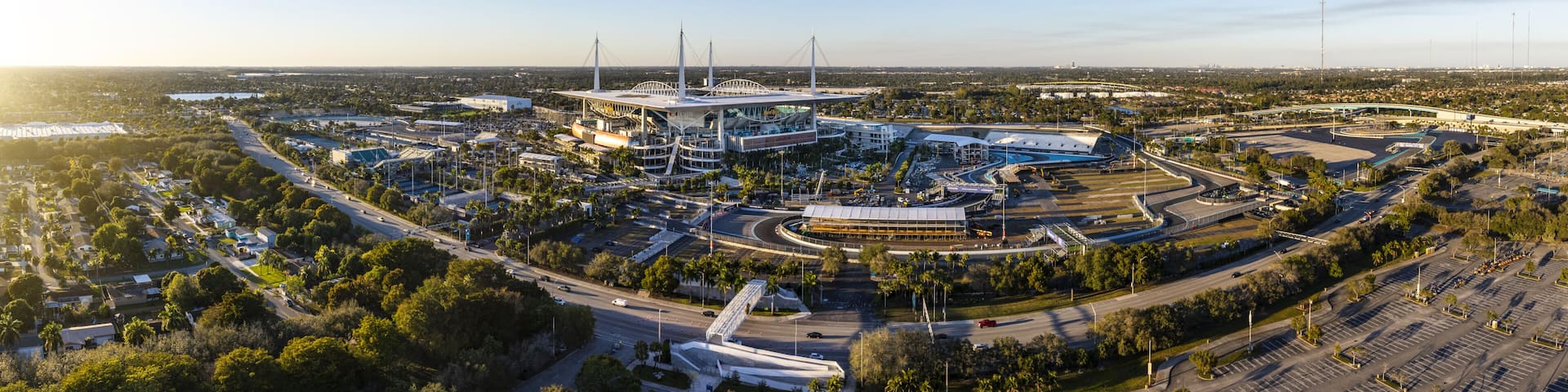 Miami Gardens, USA - 23 February 2026: Aerial view of Hard Rock Stadium bathed in the warm glow of a setting sun, its sleek architecture contrasting with the surrounding lush greenery.