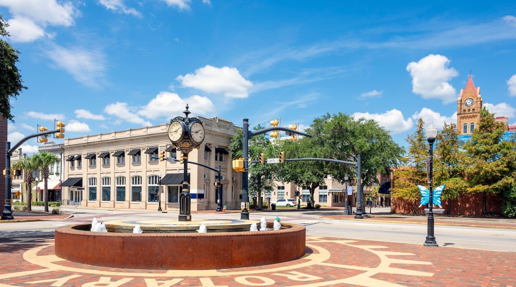A historic downtown street with a prominent clock tower, a roundabout with directional arrows, and classic architecture.