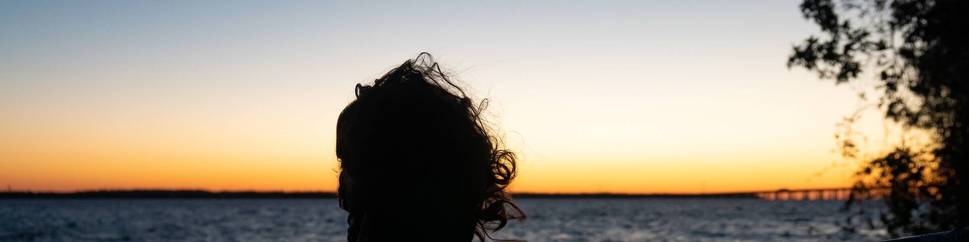 Girl in silhouette staring at the sunrise over Lake Marion in Santee State Park South Carolina
