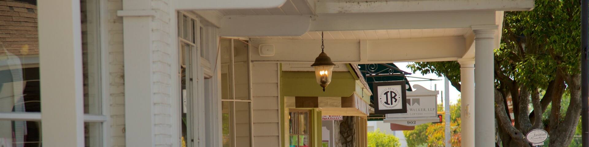 A sidewalk with a sign that reads "Swing on by!" and another sign indicating "Initial Reaction" and "We're on Facebook & Instagram."