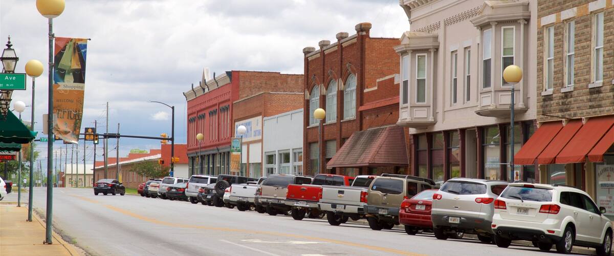 A street lined with historic buildings, parked cars, and street lamps.