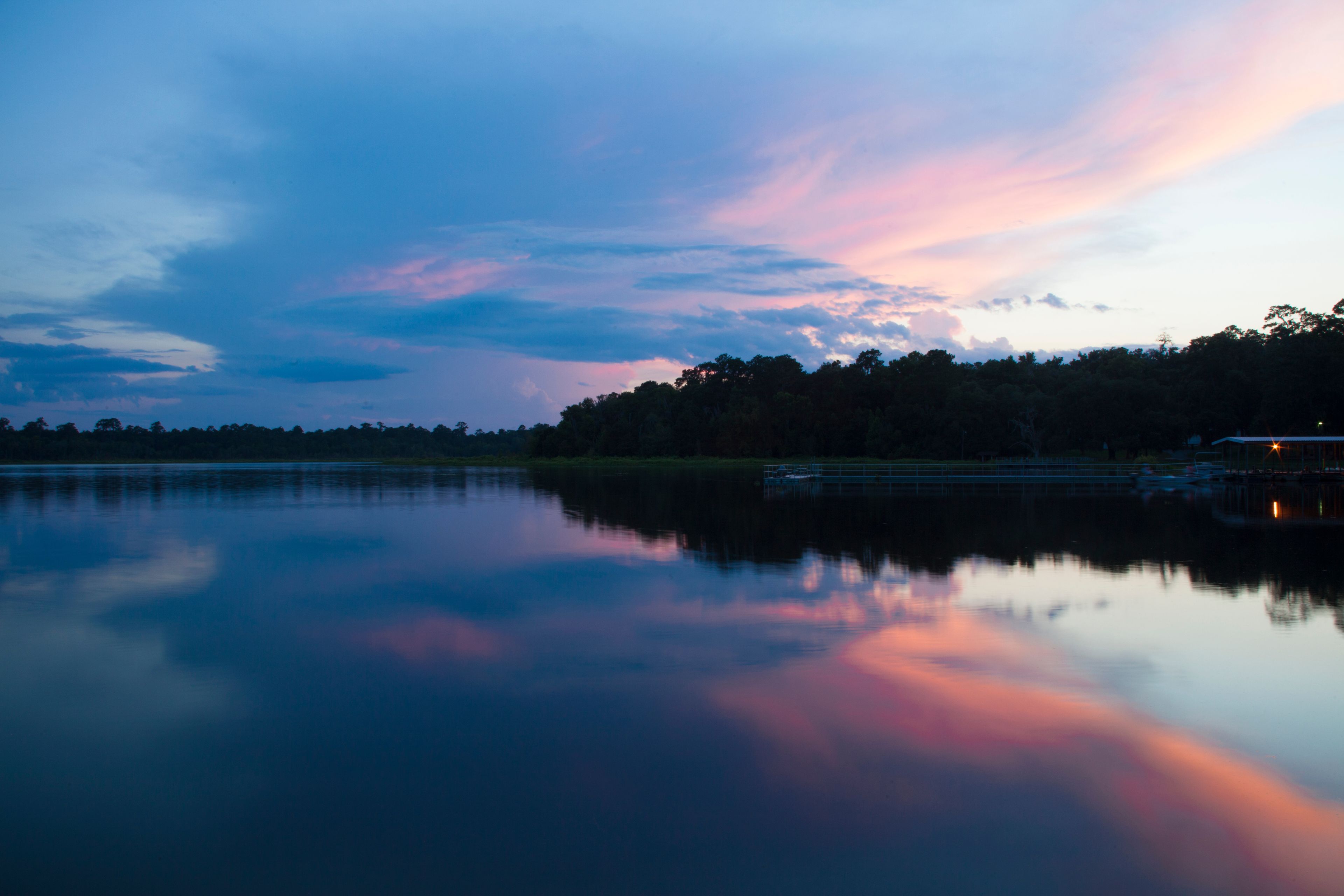 A calm lake at dusk with a reflection of the sky.