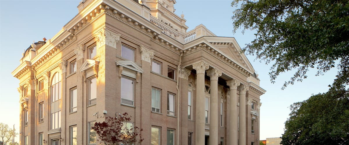 A large, historic building with classical architecture, featuring columns, large windows, and a symmetrical facade.
