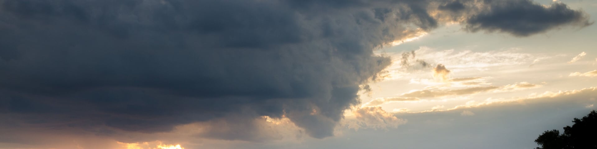 Una persona sentada a orillas de un lago durante el atardecer, con nubes espectaculares.