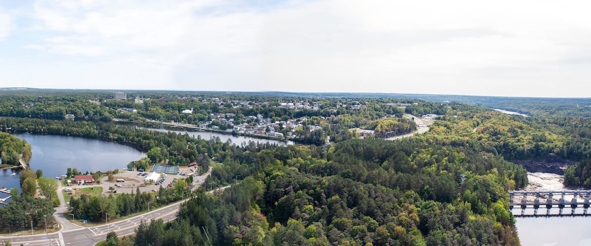 A lake surrounded by dense forest, a small town, and a dam.