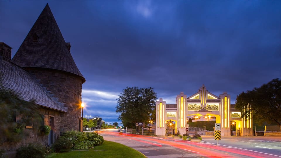 A stone tower and a modern building with illuminated windows at dusk.
