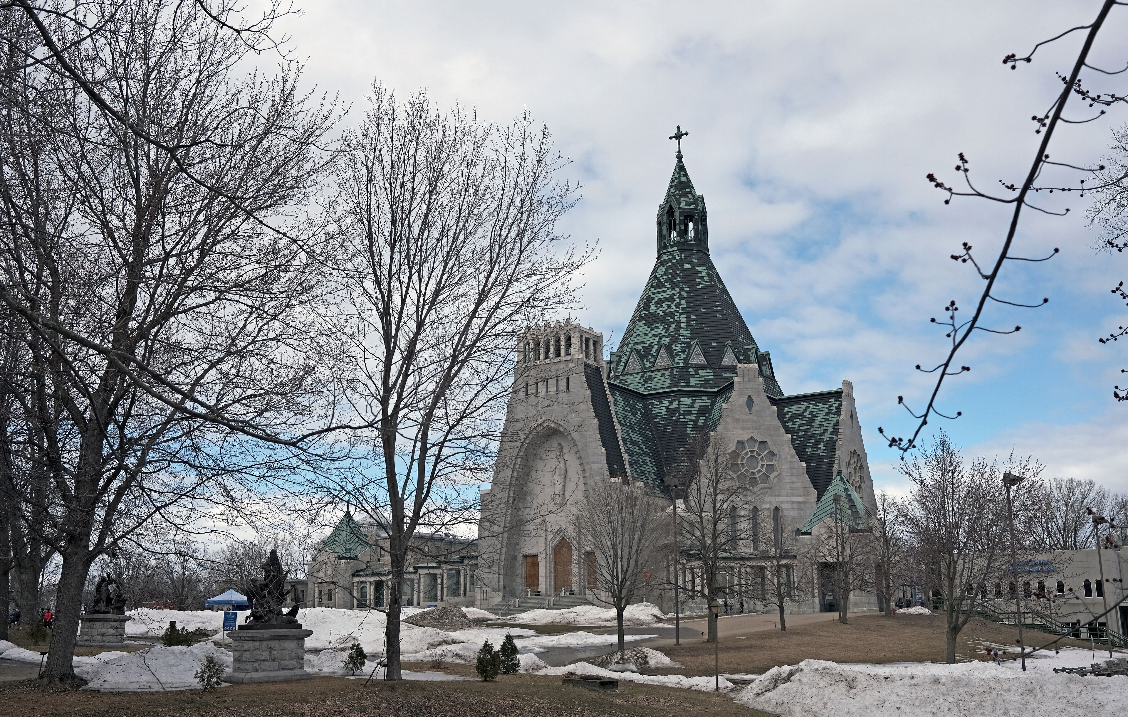 A historic church with a tall spire and a statue in the foreground.