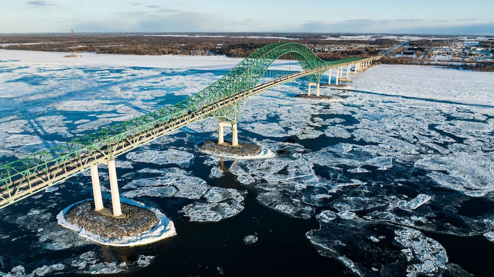 A green bridge over a frozen river with ice floes.