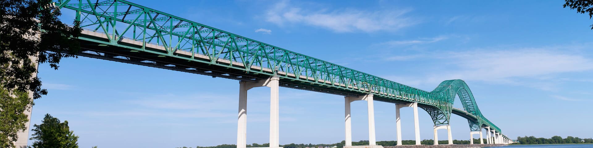 A green steel bridge with a curved section spanning a river.