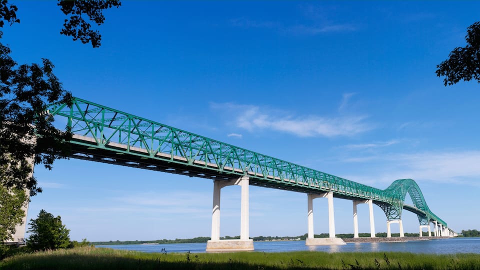 A green steel bridge with a curved section spanning a river.