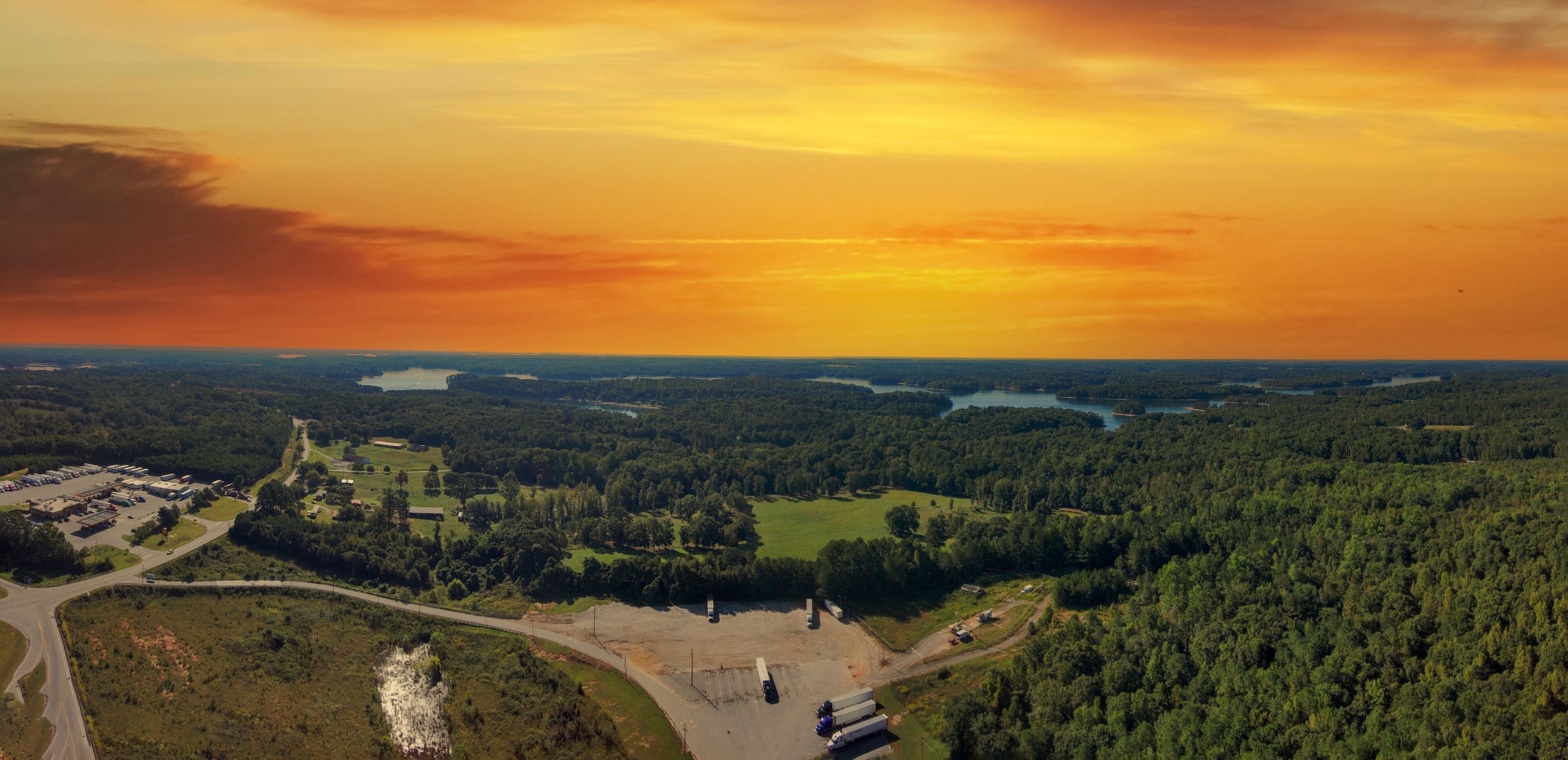 a stunning aerial panoramic shot of the blue waters of Lake Hartwell surrounded by vast miles of lush green trees and grass with powerful clouds at sunset in Fair Play South Carolina USA