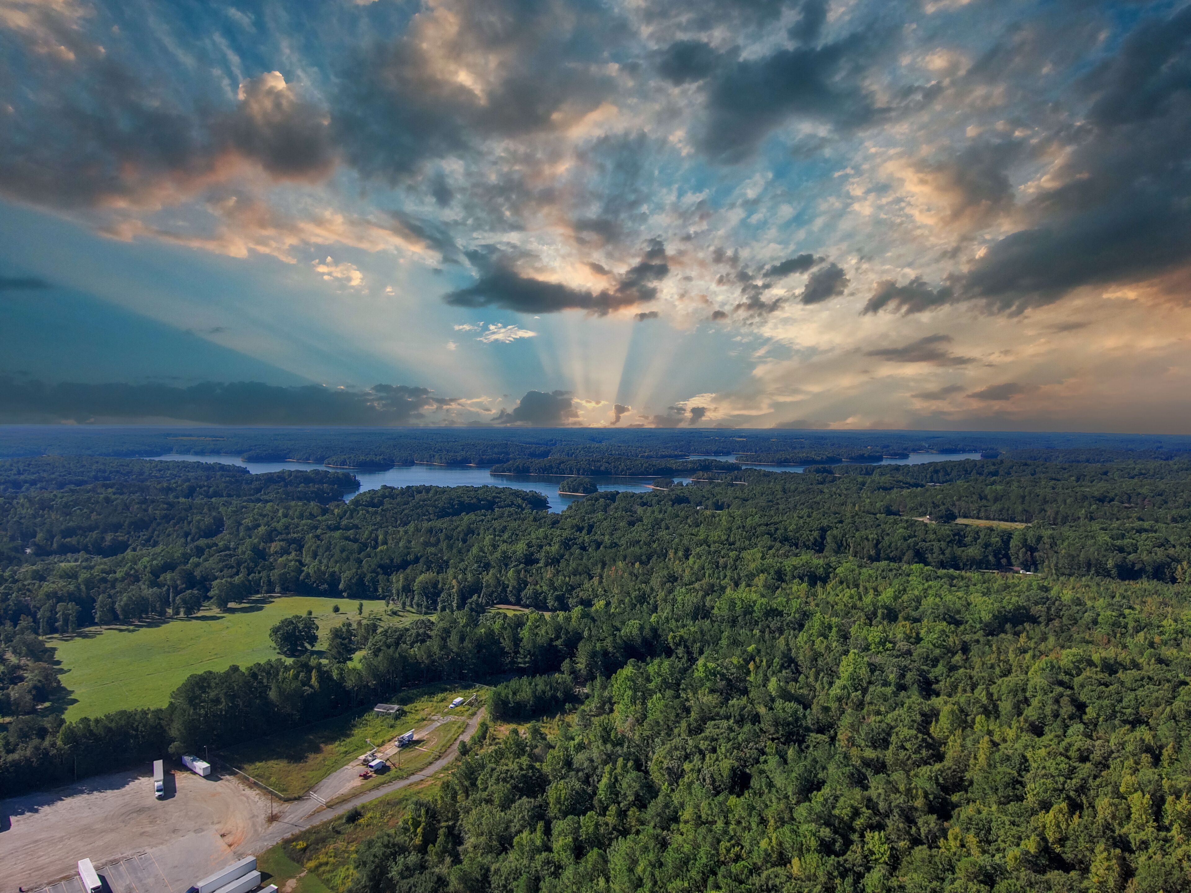 a stunning aerial shot of the blue waters of Lake Hartwell surrounded by vast miles of lush green trees and grass with powerful clouds at sunset in Fair Play South Carolina USA
