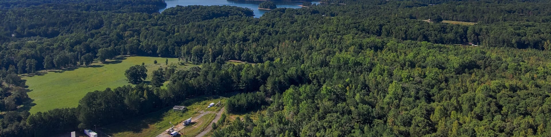 A forested landscape with a river and scattered buildings.