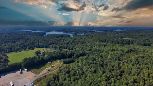 a stunning aerial shot of the blue waters of Lake Hartwell surrounded by vast miles of lush green trees and grass with powerful clouds at sunset in Fair Play South Carolina USA