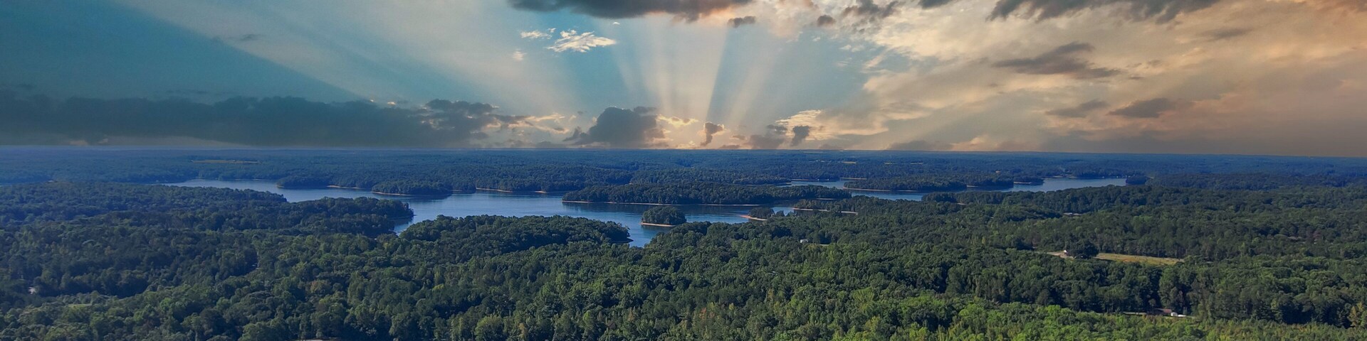 Un paisaje boscoso con un río y edificios dispersos.