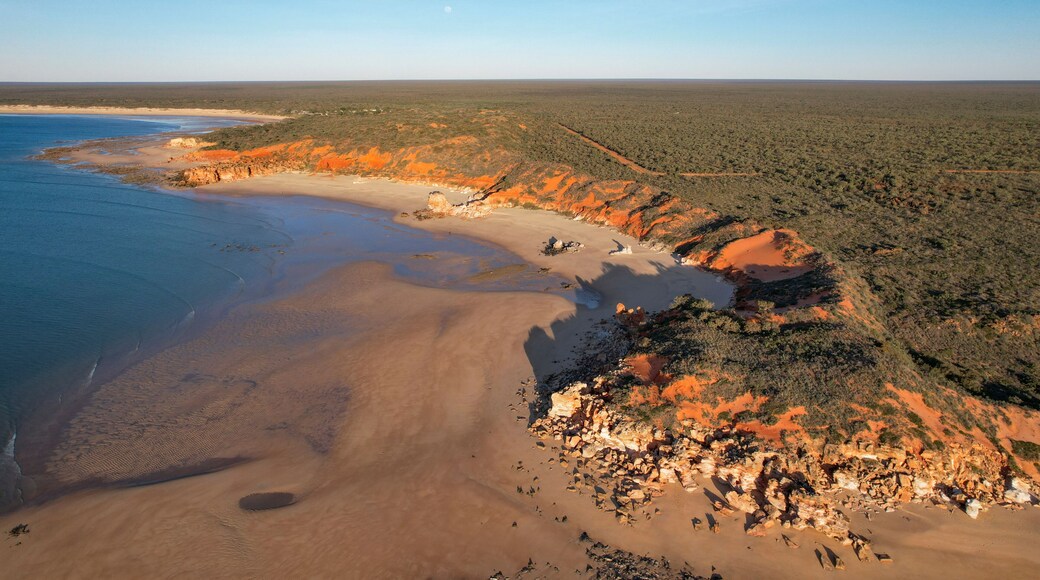 Aerial view of echo beach resort coastline with ochre cliff and the moon, Lagrange, Western Australia.