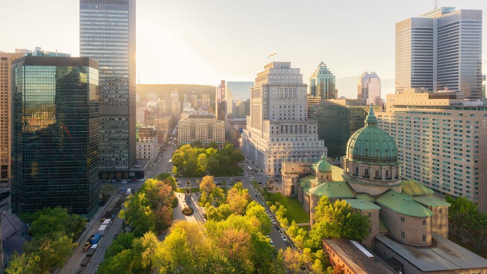 Golden hour aerial view of downtown Montréal, Québec, with Mary, Queen of the World Cathedral surrounded by the city's modern skyline and vibrant foliage
