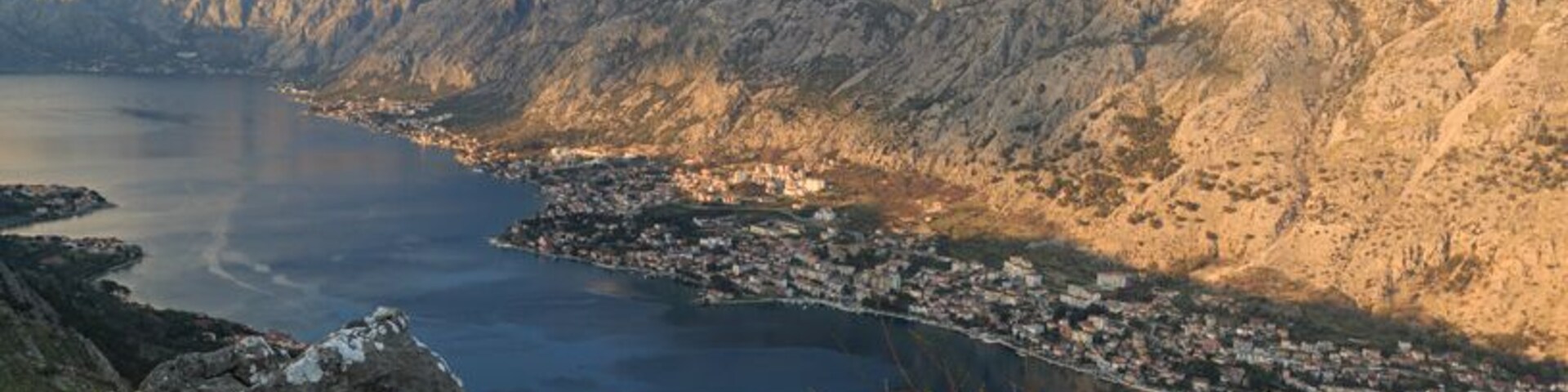 Atop the mountain opposite of Kotor Old Town is a 3.5km walking path. Walk towards Muo. As soon as you enter the town there is a green sign post to turn left to get to the walking path. Follow the road until you find stairs on the right hand side marked with a red and white dot. Follow the stairs up until you get to the road. On the right is a driveway. Just to the left of the driveway is a hill (it doesn't look like much) and this is where the path starts. Follow this for 3.0km via switchback up the mountain and you will arrive to a crossroads where there is a camp. Turn left to go to this viewpoint (in picture) or continue right to view the other side of the mountain, an outstanding view of Tivat.