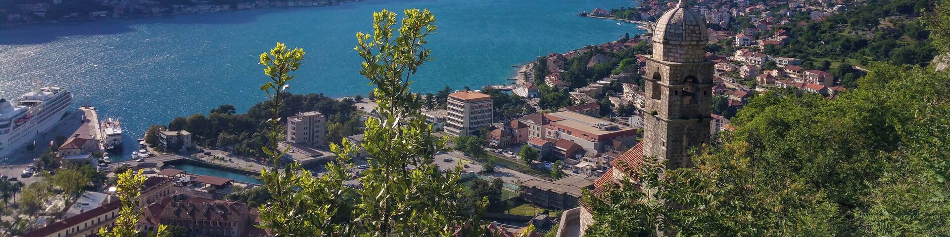 A coastal town with a prominent church, mountains, and a clear blue lake.