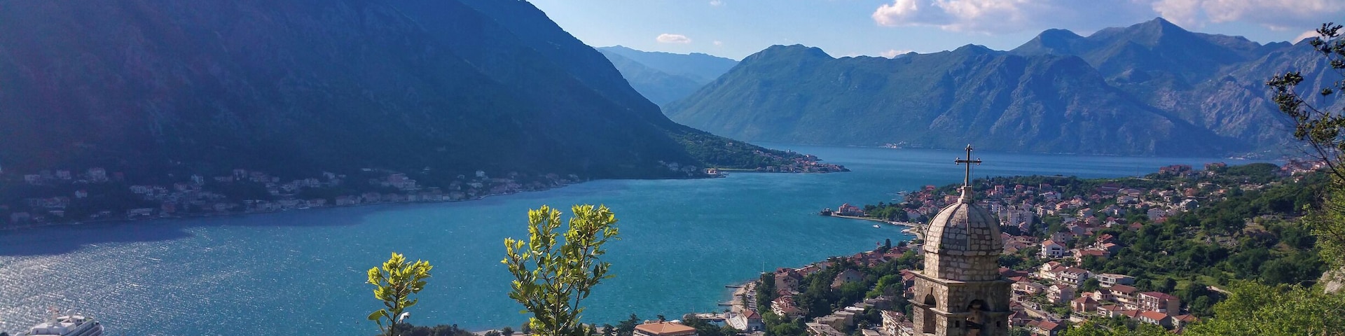 Uma vila costeira com uma igreja imponente, montanhas e um lago azul límpido.