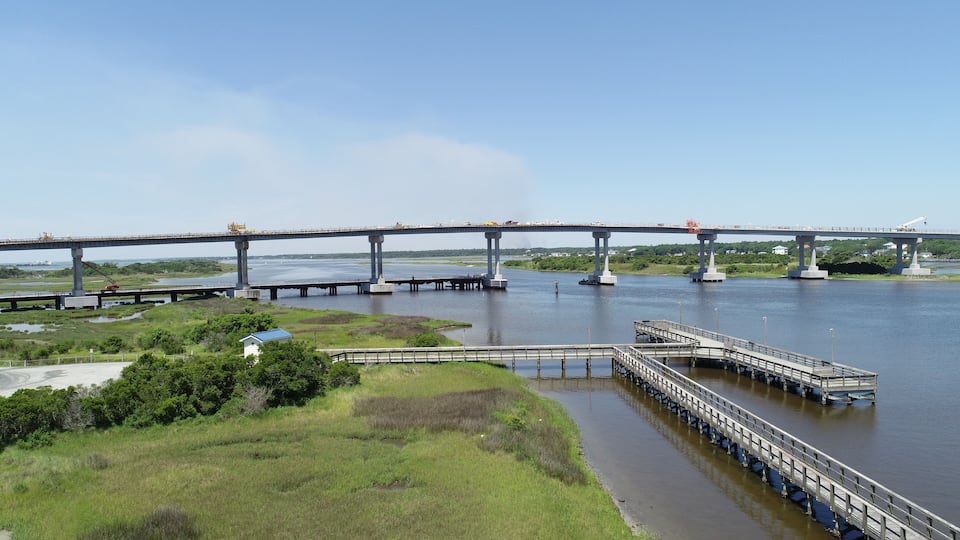 A large bridge spanning a river with a dock and a small building in the foreground.