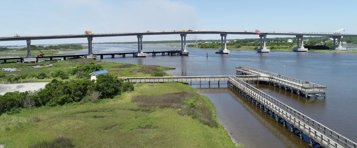 A large bridge spanning a river with a dock and a small building in the foreground.