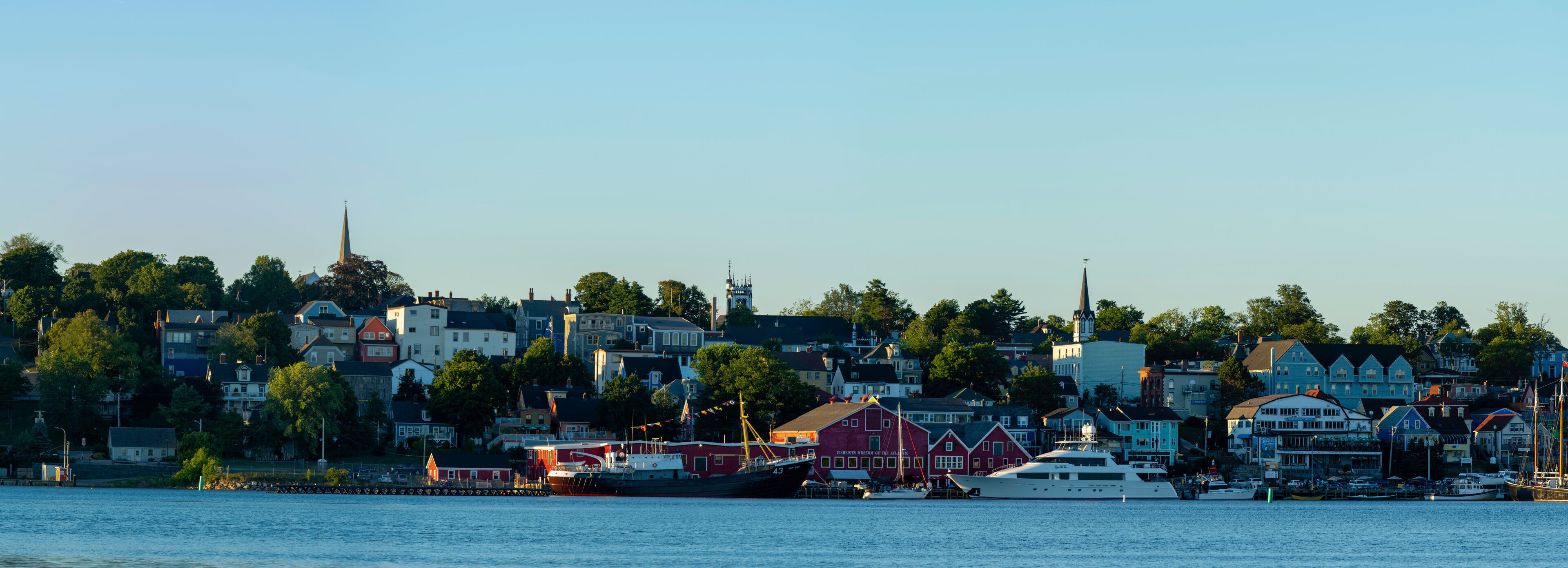 A harbor with boats, a church steeple, and houses along the waterfront.