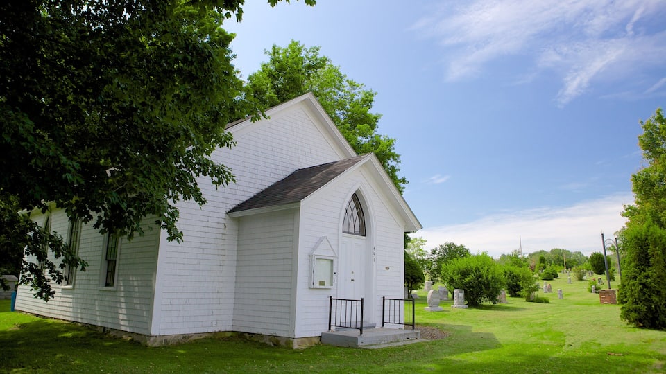 A white church with a steeple, surrounded by a cemetery with gravestones.