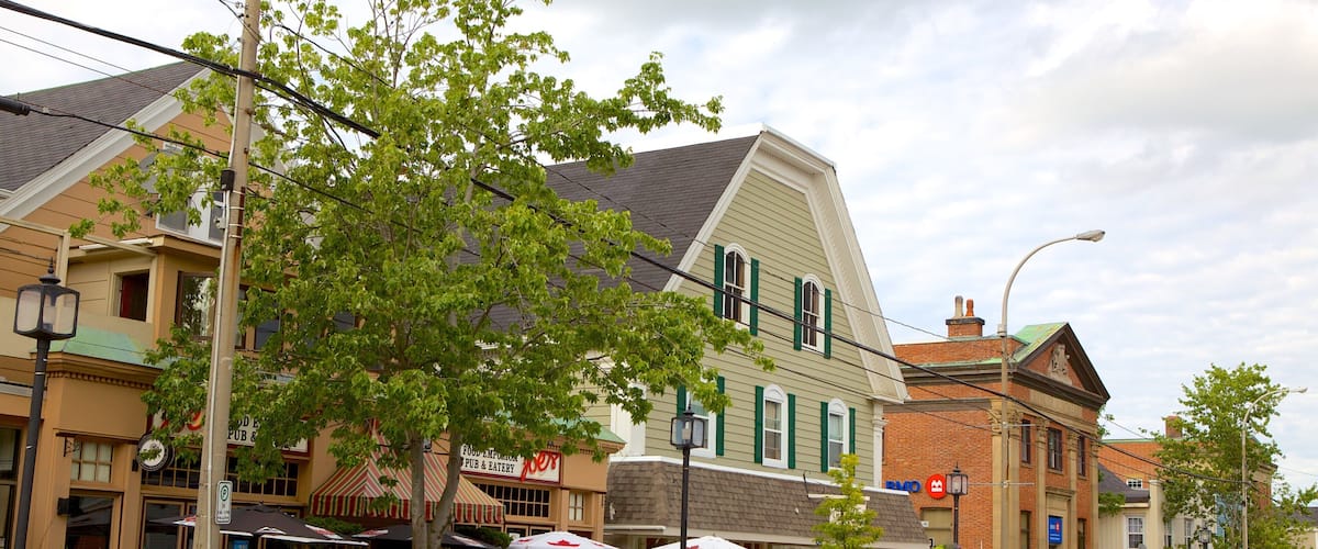 A street with buildings, outdoor seating, and a car.