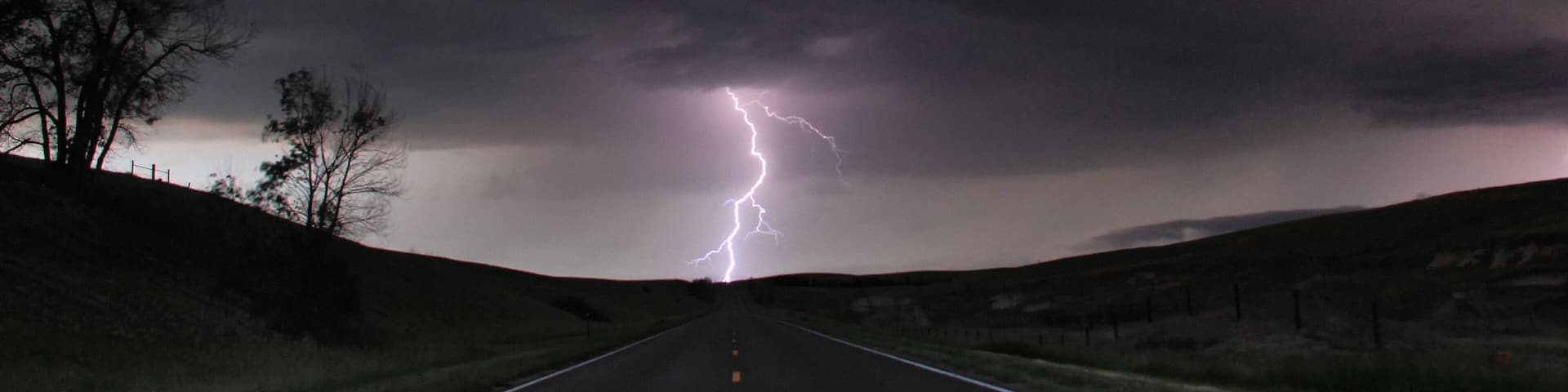 A single cloud-to-ground bolt lands at the end of a rural road, Lexington, Nebraska, USA