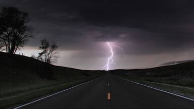 A single cloud-to-ground bolt lands at the end of a rural road, Lexington, Nebraska, USA