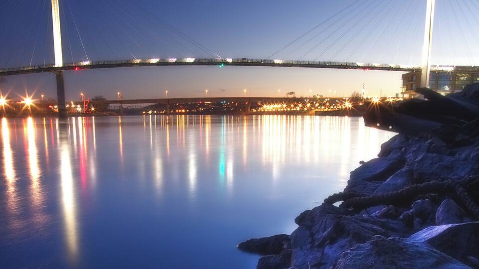 A bridge at dusk with lights reflecting on the water.
