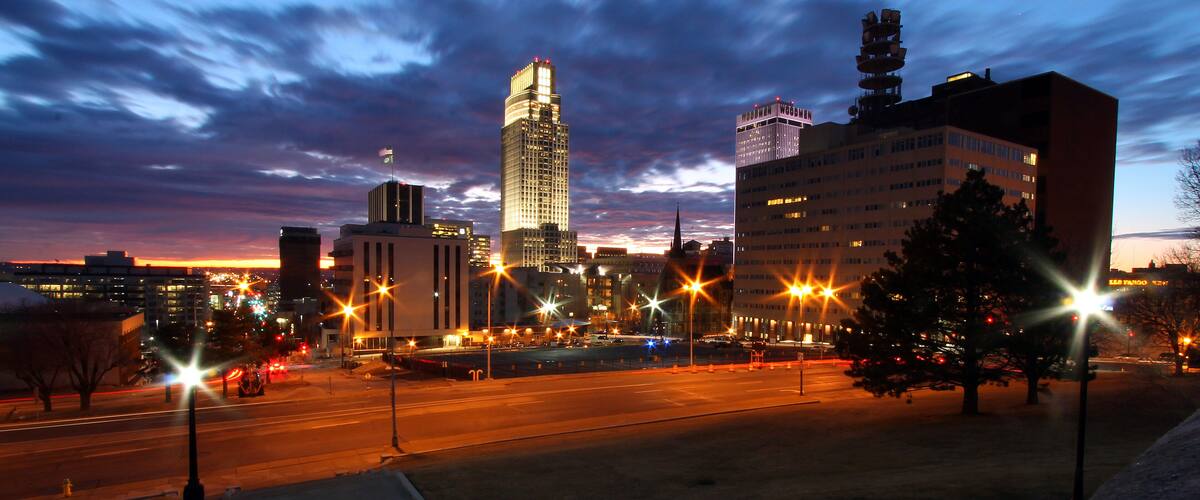 A cityscape at dusk with illuminated buildings and a clear sky.