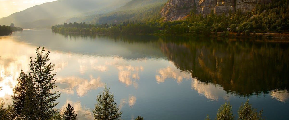 A calm lake surrounded by mountains and trees.