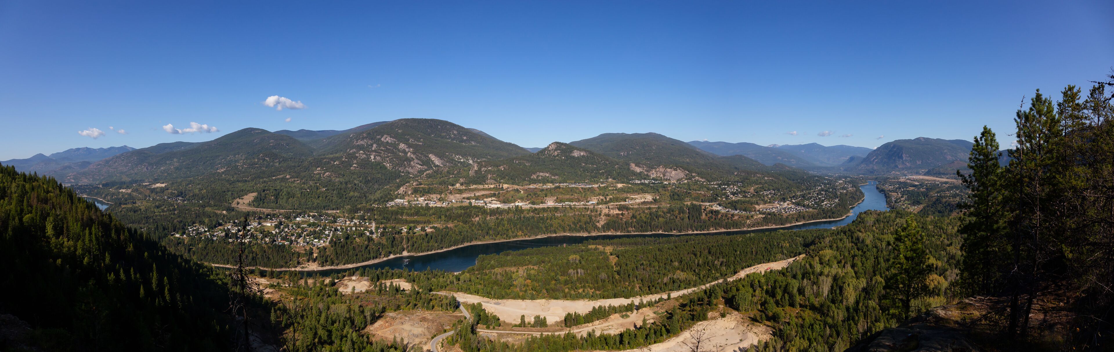 A mountainous landscape with a river, forested areas, and a small town.